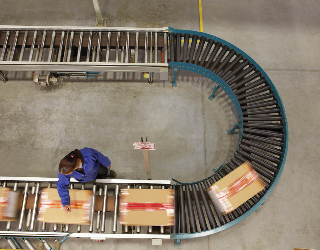 Elevated view of female worker scanning boxes on a conveyor belt in a warehouse