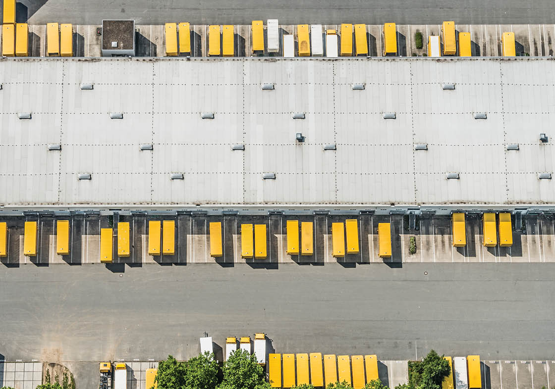 Postal logistics center with parked yellow trucks and truck trailers, aerial view